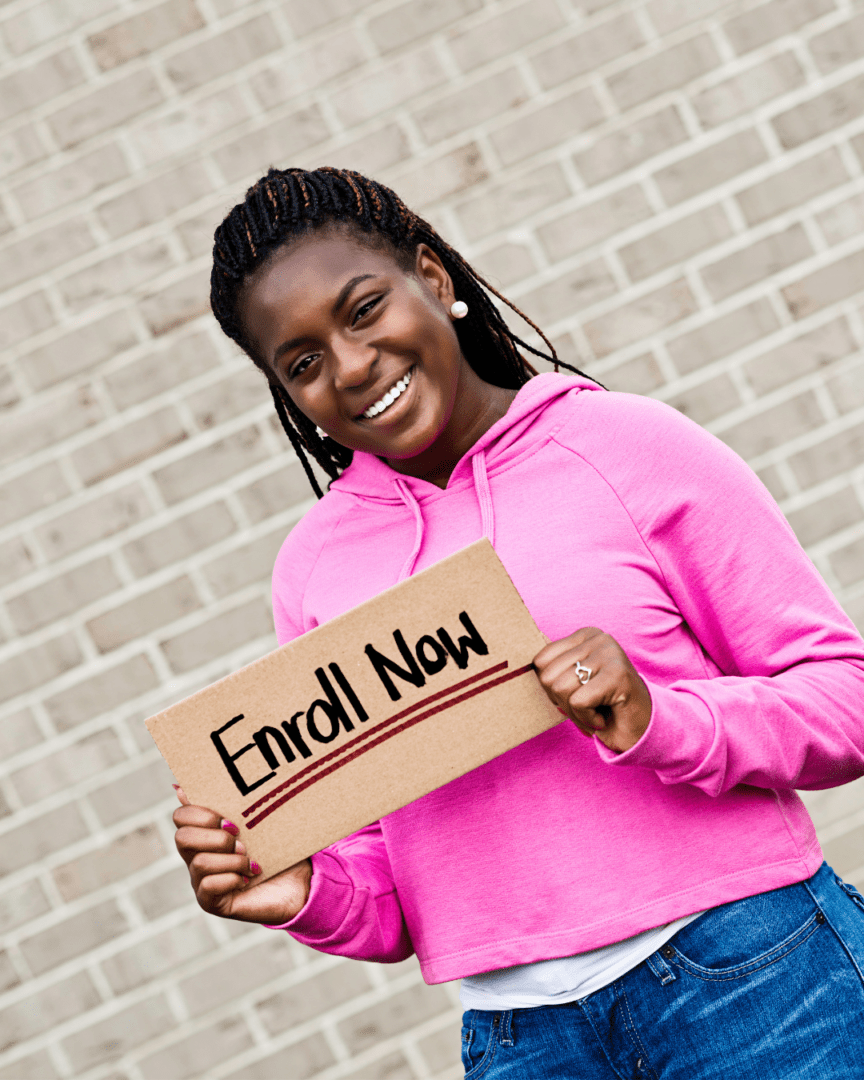 Early College student holding a sign that reads "Enroll Now"