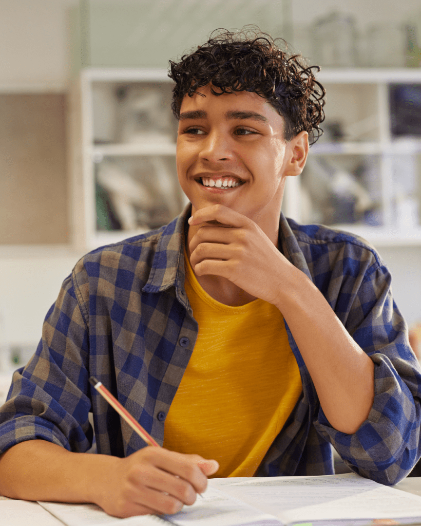 Early College student sitting at a desk with paper and pencil.